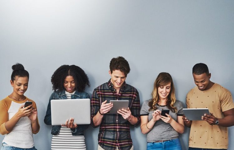Studio shot of a group of young people using wireless technology against a gray background